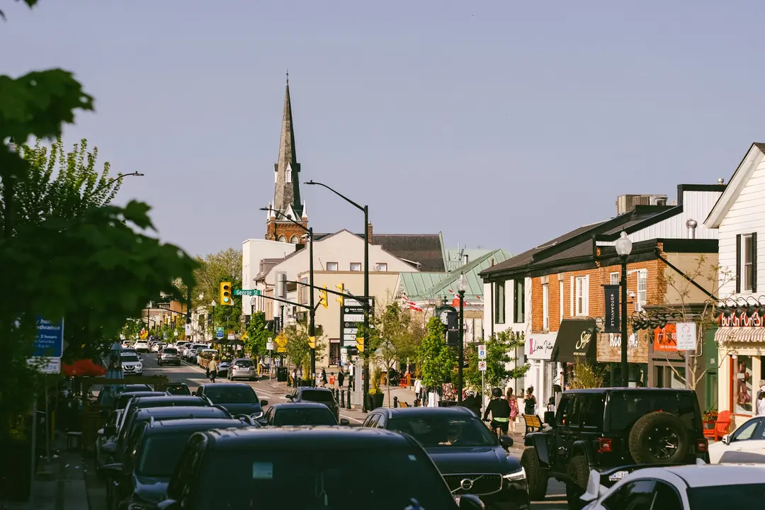 Shops, a church spire and people on a main street in downtown Oakville