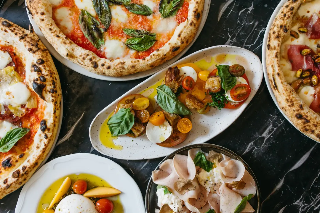 Wood-fired pizzas and small plates on a marble table at 7 Enoteca